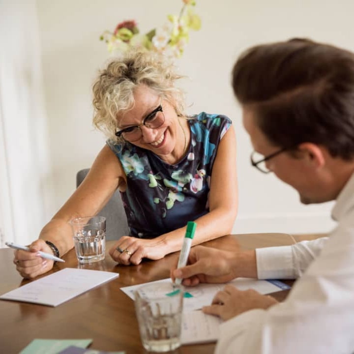 Therapeut therapie Vrouw lacht tijdens een coachingsgesprek aan tafel met een mannelijke professional
