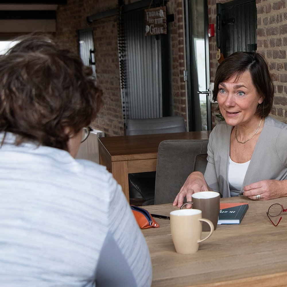 DISC-gedragsanalyse met een coach Vrouwelijke psycholoog in gesprek met coachee tijdens DISC analyse, zittend aan tafel met koffie