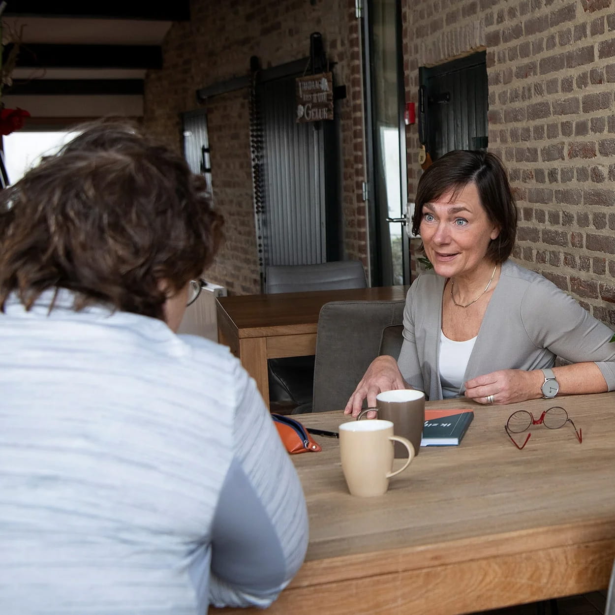 Gesprekssessie aan tafel met twee personen over postnatale depressie en emotionele ondersteuning