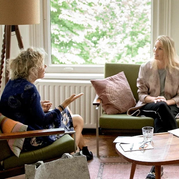 Therapeutisch gesprek tussen twee personen in een rustige en professionele praktijkruimte.